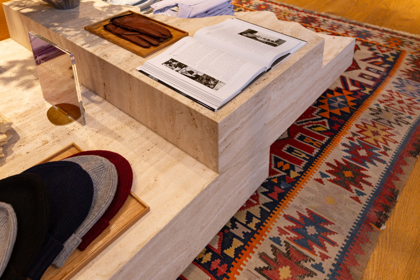 Gant Store Stockholmi luksuslik interjöör: beež kivist kandjaga müügikp, kirjandusalbum ja raamatukogusarnased detailid, tugevamatäpilised rugid lisavad kontrasti.
