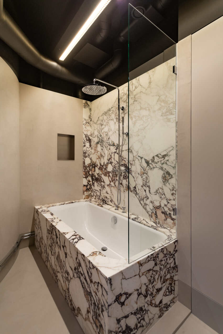 Apartment Max - Marmi Futerno marmormotiiviga vannitoa kujundus, valge marmormustritega vann, läbipaistev klaasvahesein ning musta laki detailid, elegantne dušikabiin ja kaasaegne interjöör.