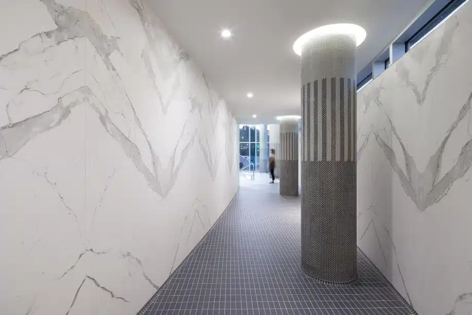 Hallway with Bianco Statuario Venato marble walls and patterned columns.