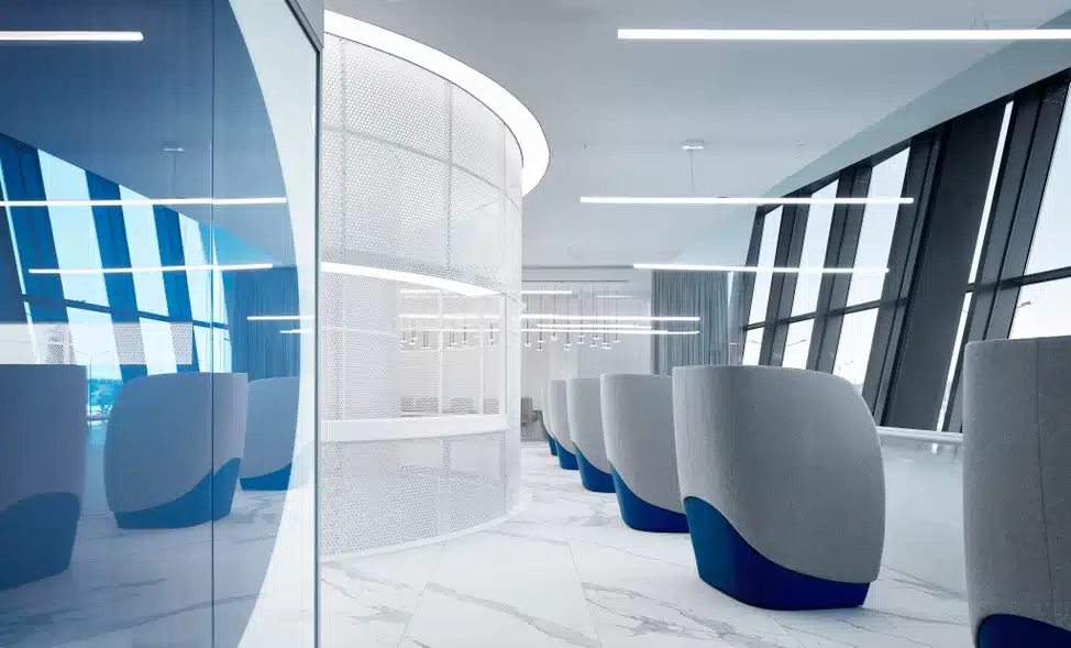 Modern office lounge area with Bianco Statuario Venato marble flooring, curved wall, and stylish seating pods.