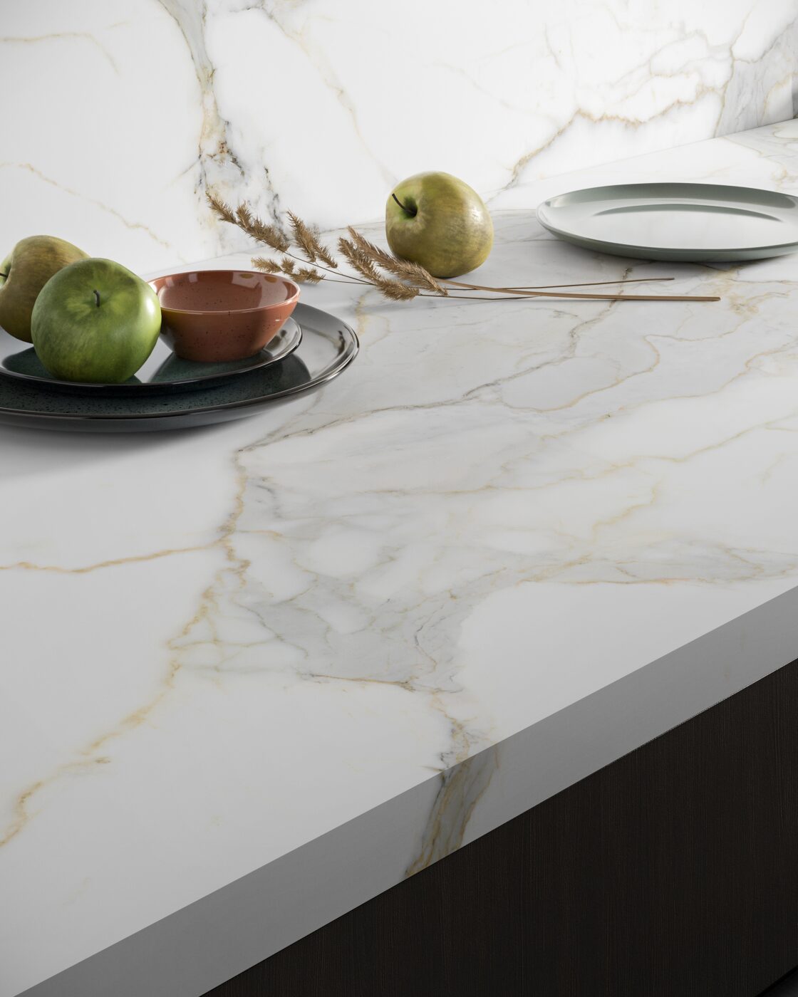 Calacatta Michelangelo Laminam marmorpõhine pind valge taustal, kuldsed veeringud, peene tekstuur, elegantne köögiprahvi pind ja puitlõikelaud serval.