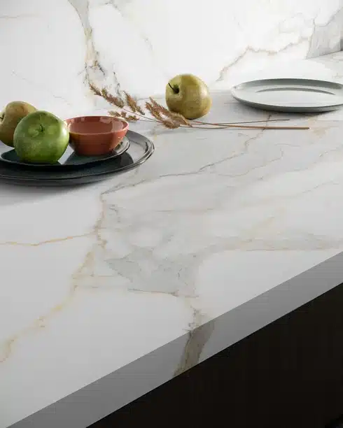 Calacatta Michelangelo quartz countertop with apples and a bowl, showcasing its elegant marble-like design.