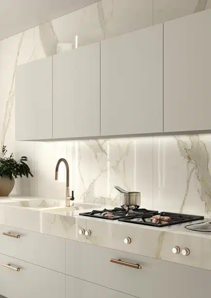 Calacatta Michelangelo marble kitchen with sleek cabinets, gold hardware, and gas stovetop.