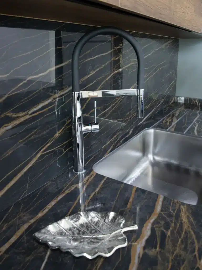 Modern kitchen sink with Noir Desir marble countertop and sleek faucet.