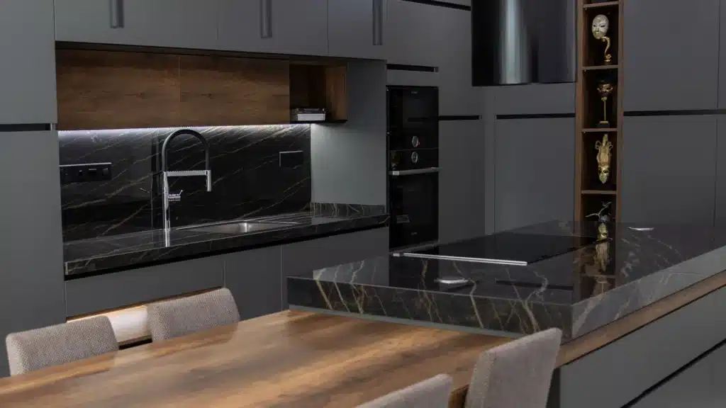 Noir Desir kitchen featuring dark marble counters, gray cabinets, and a wooden dining table.