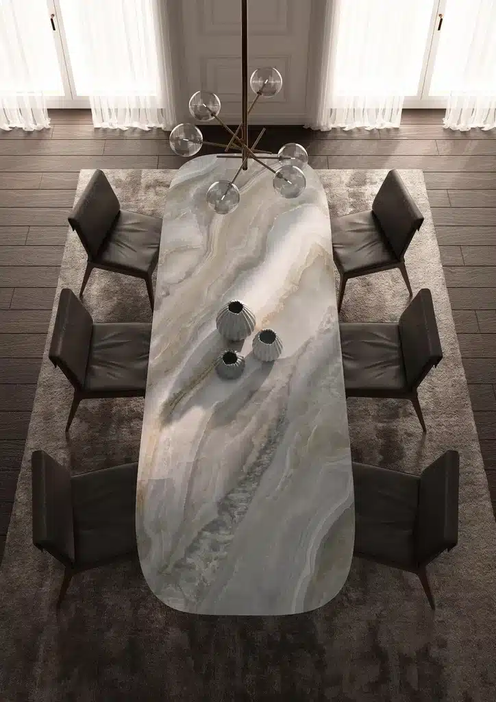 Onice Grigio Laminam laud näidatakse marmormustriga hallikas-valge toonides plaat, mis sobib kaasaegse interjööriga; laua ülaosa voogavad toonid ja salleid ning tumedad toolid ümber.