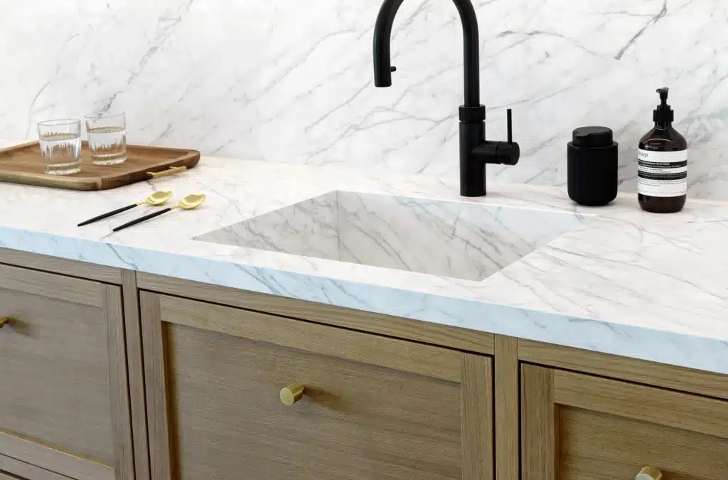 Statuarietto marble countertop with integrated sink, black faucet, and wooden cabinets.