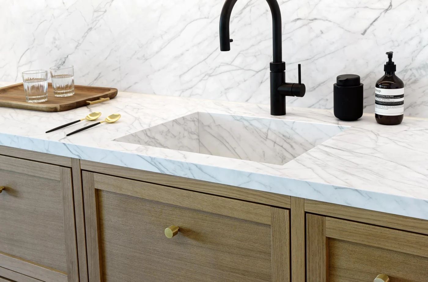 Statuarietto marble countertop with integrated sink, black faucet, and wooden cabinets.