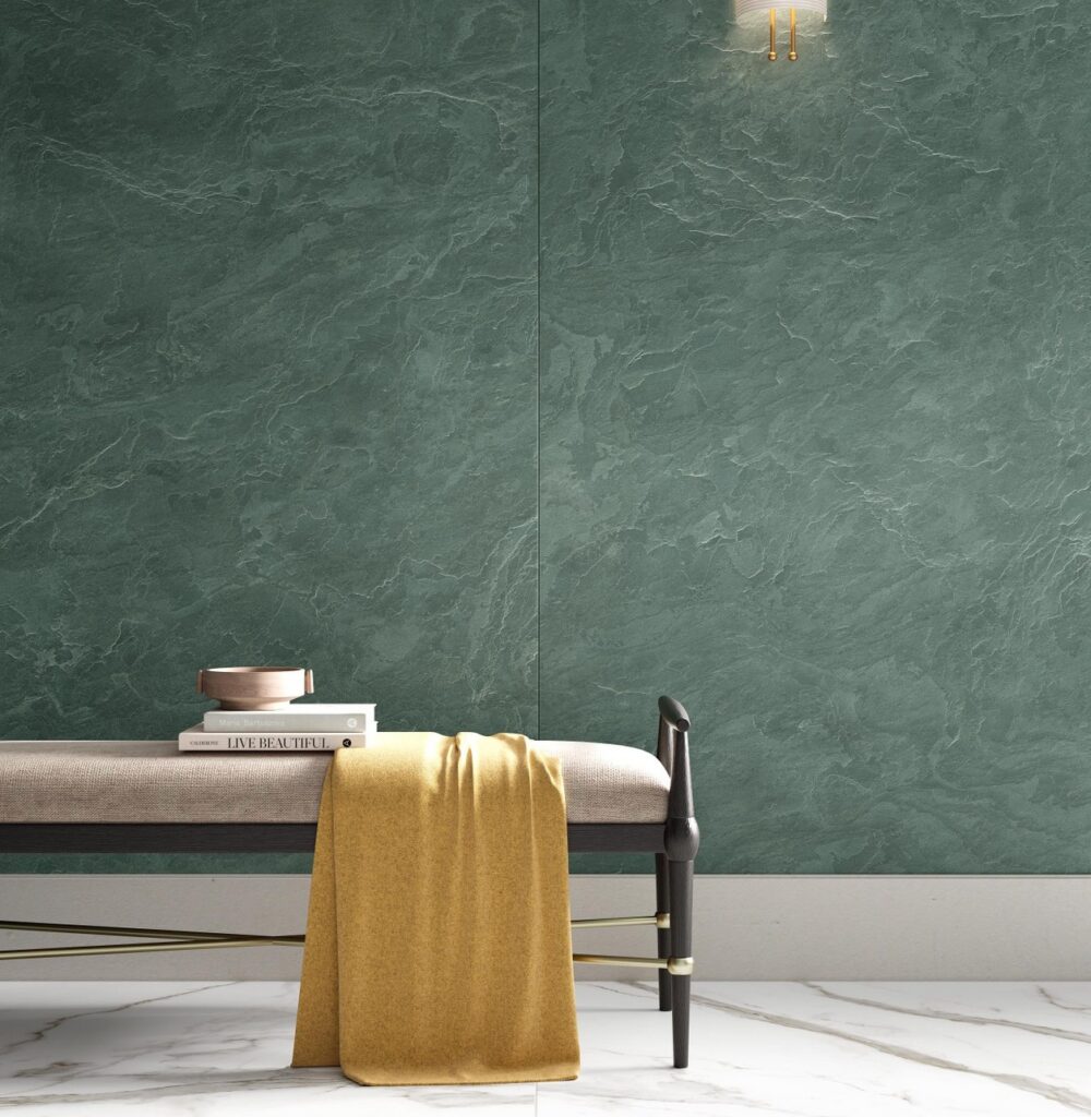A green Laminam Amazzonia wall panel with marble-like veining, set in a stylish interior featuring a bench, a mustard throw, and a marble floor.