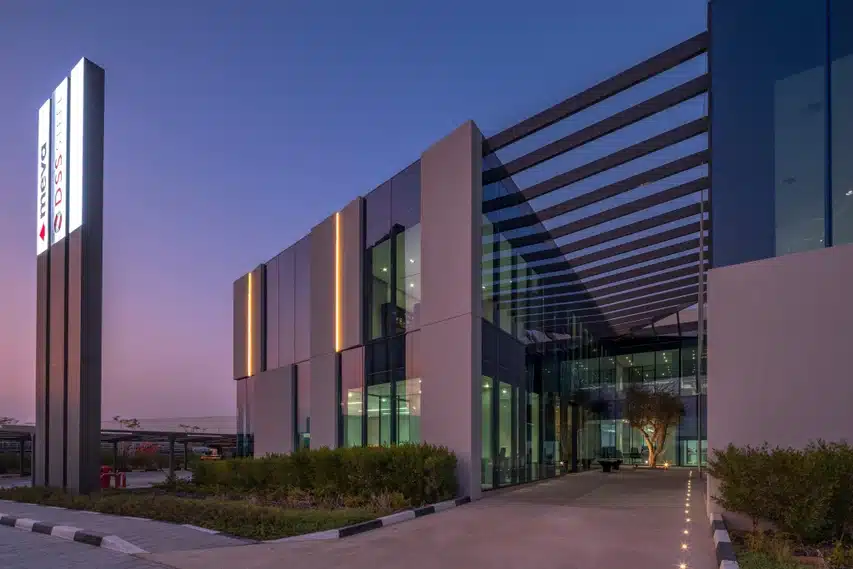 Tumeroheline-kollakas kliimimisk joonega hoone esiplaanil eranäitus, modernne Laminam Calce Antracite plaanid, valgusillutised ja suure klaasfassaadiga fassaad, Calce Antracite ja Laminam tähistused.