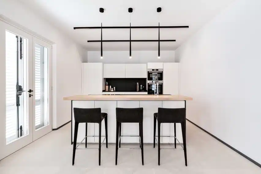 Calce Bianco Laminam'i valge pindadega kaasaegne kööginurk, kus suur saare ja mustade toolidega minimalistlik disain ning rippvalgustid loovad arhitektuurse ilme