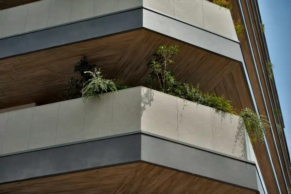 Piombo–värvi Laminam Fokos, hallide kivilaadsete puitkonstruktsioonidega hoone piirkond, mille terrace- või balustradidel on pruunid elemendid ja rohelised taimed