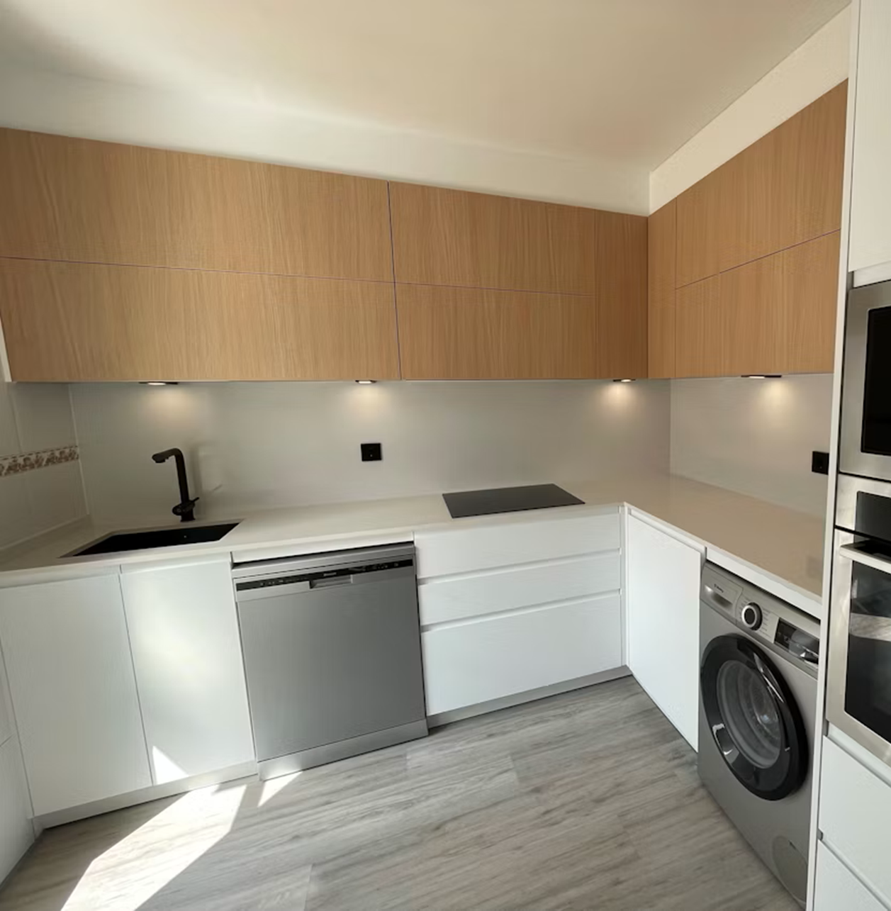 Bright Silestone Miami White quartz kitchen with wood cabinetry, integrated sink, dishwasher, induction hob and under-cabinet lighting in a modern layout.