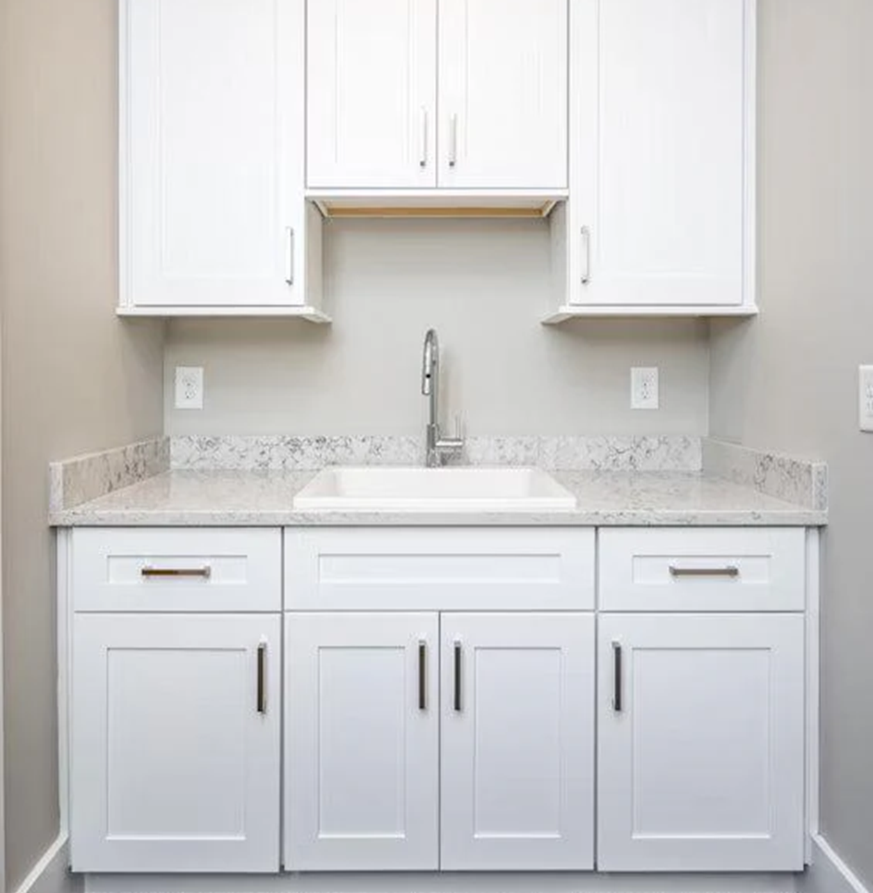White laundry room cabinets and Silestone Helix countertop with sink.