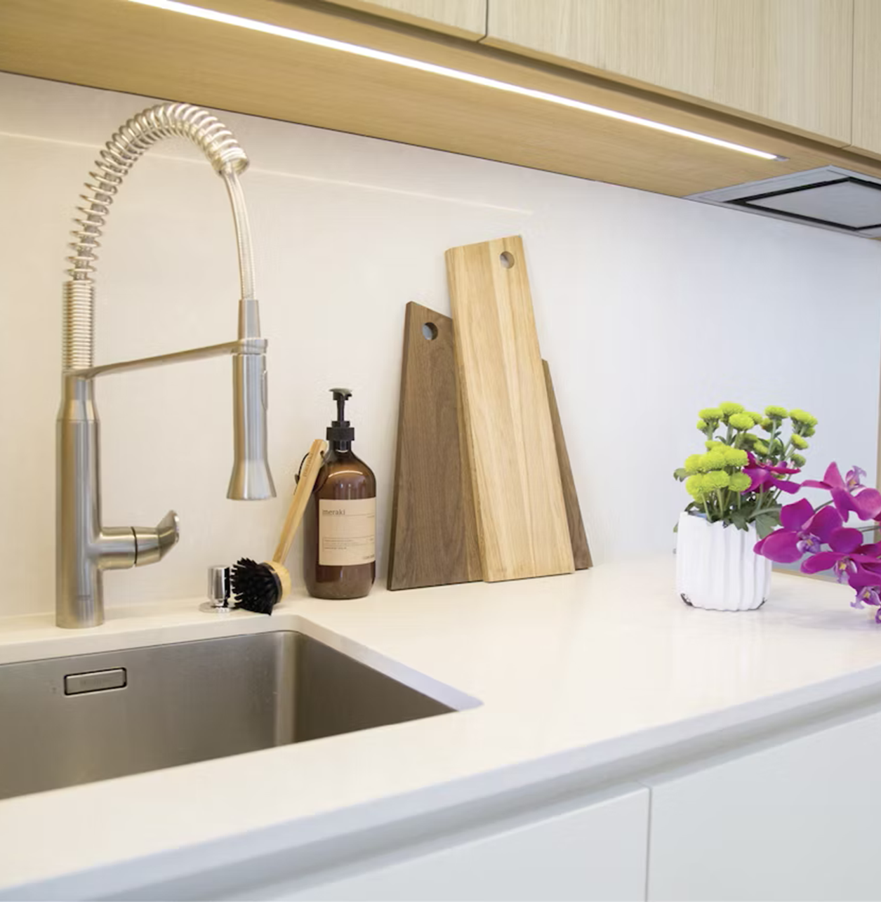 Modern kitchen sink with Silestone Yukon countertop, faucet, dish soap, and cutting boards.