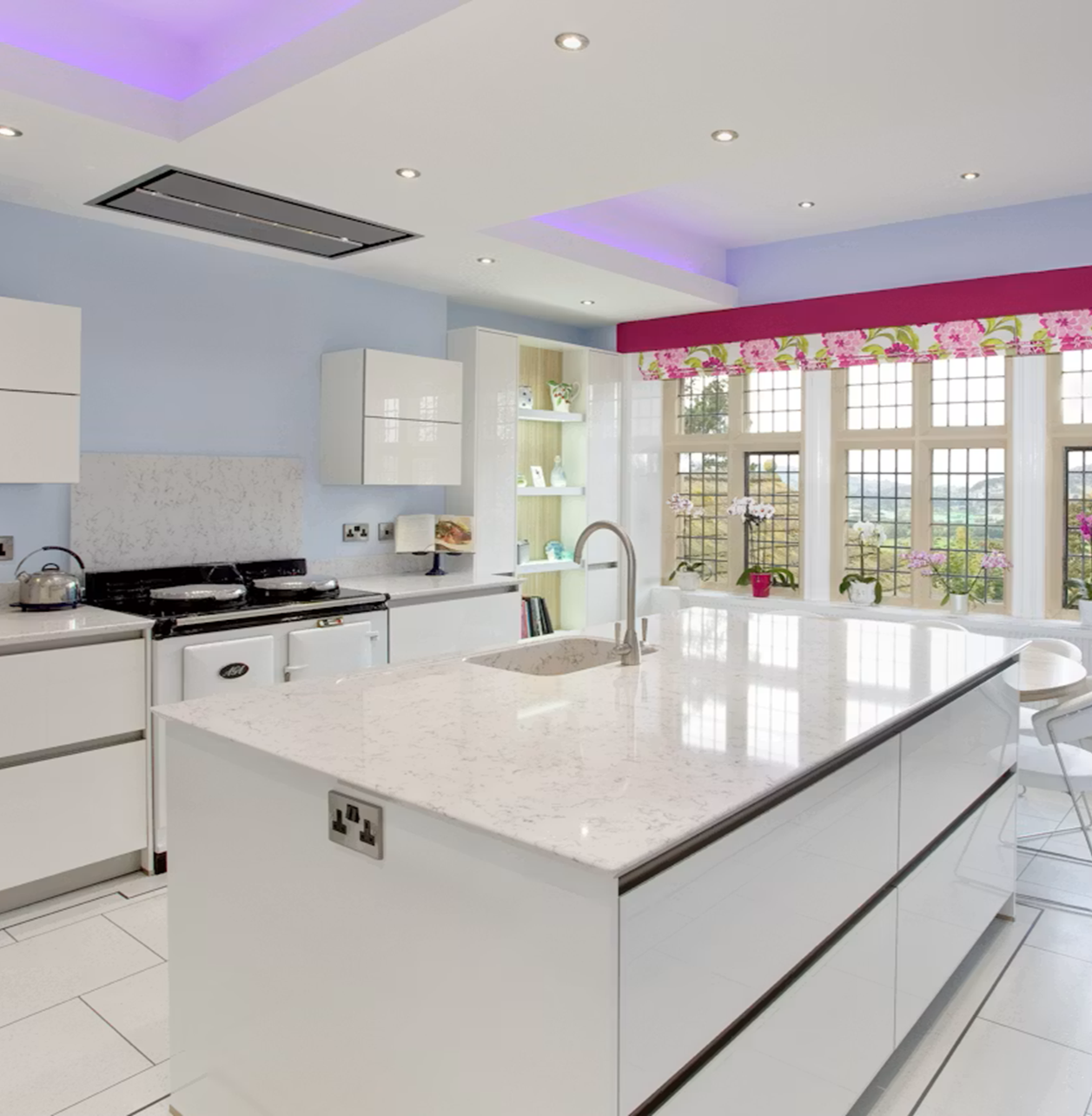 Modern kitchen with Silestone Lyra island, white cabinets, and pink window treatments.