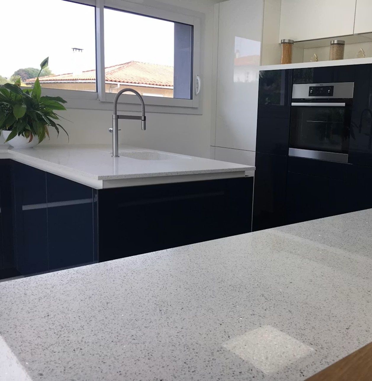 Silestone Stellar Blanco countertop in a modern kitchen with navy cabinets and sink.