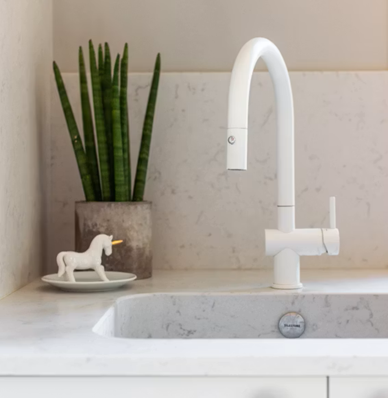 Silestone Lagoon countertop with white faucet, snake plant, and unicorn decor