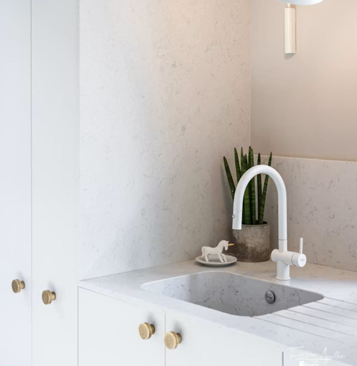 Silestone Lagoon countertop with white sink, faucet, and plant.