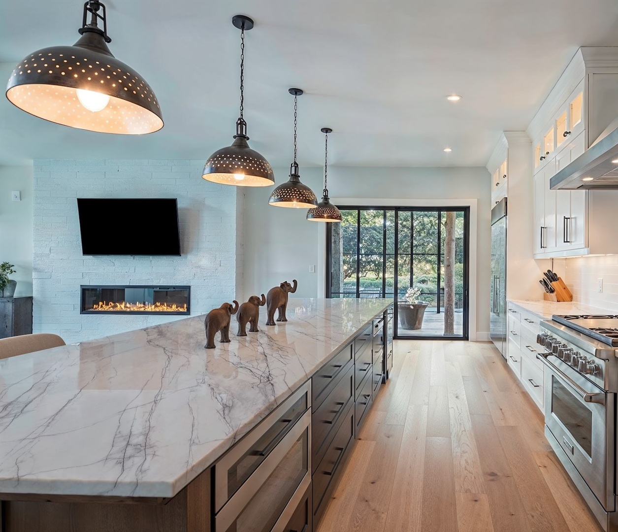 Avant Quartz 5753 Calacatta Aveyron covers a long kitchen island beneath black pendant lights in a bright modern interior.