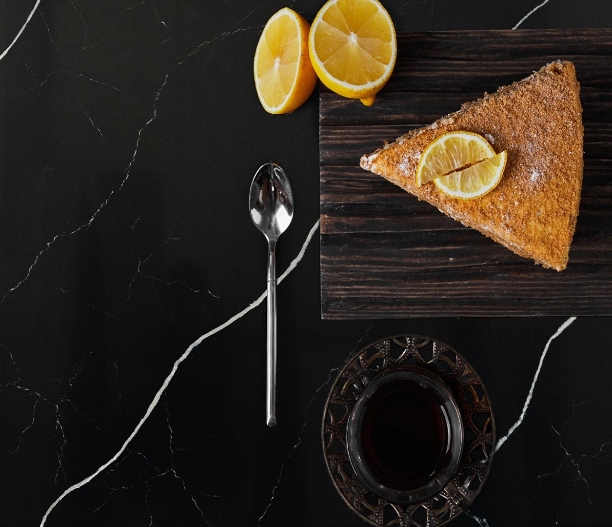 Slice of lemon cake with lemons and tea on Avant Quartz 7060 Calacatta Mont Saint-Michel countertop